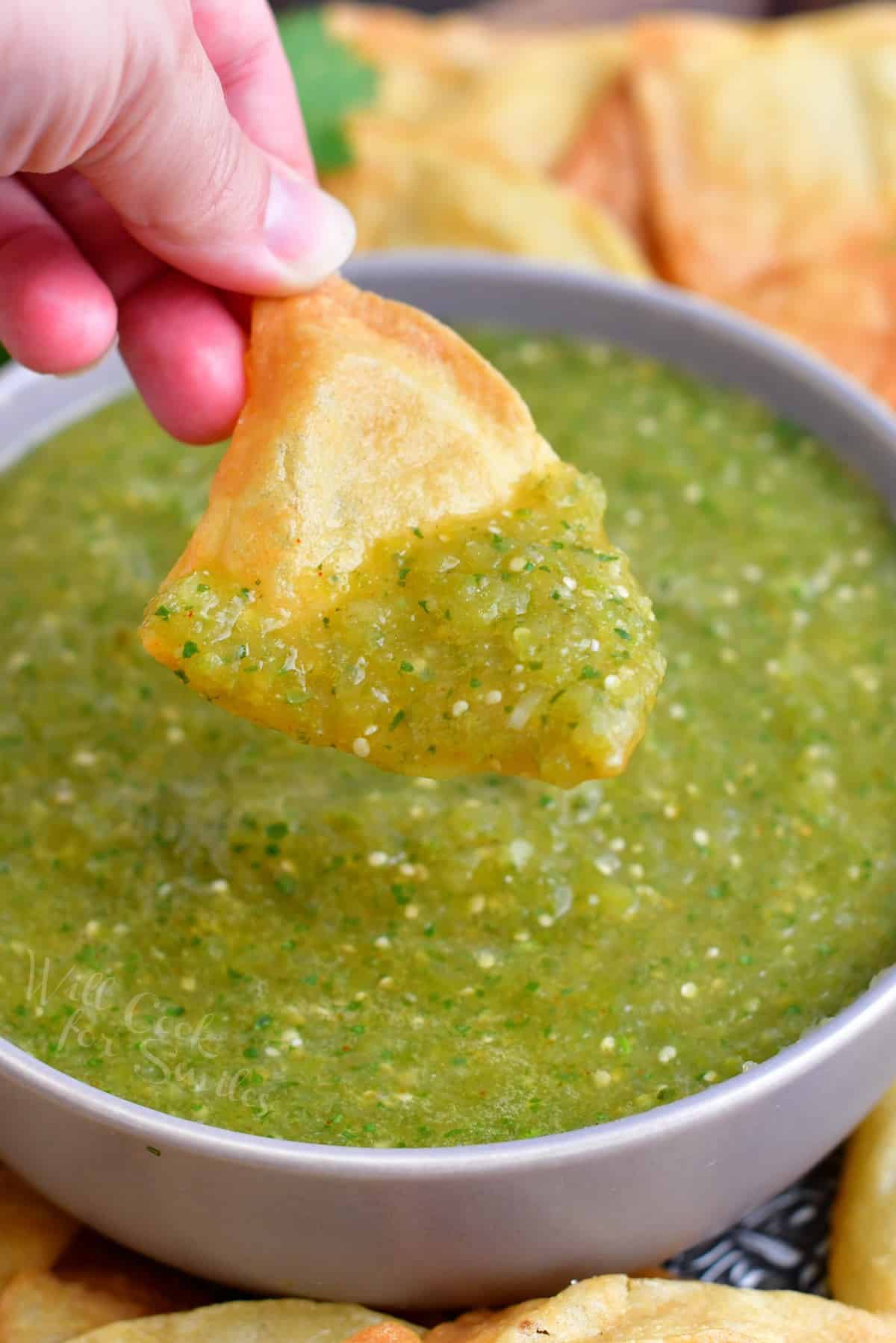 A chip is scooping a bite sized portion of salsa from the bowl.
