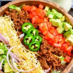 A taco salad that has not yet been tossed is in a large bowl.