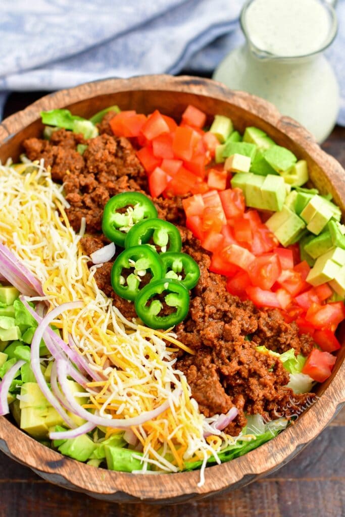 A taco salad that has not yet been tossed is in a large bowl.