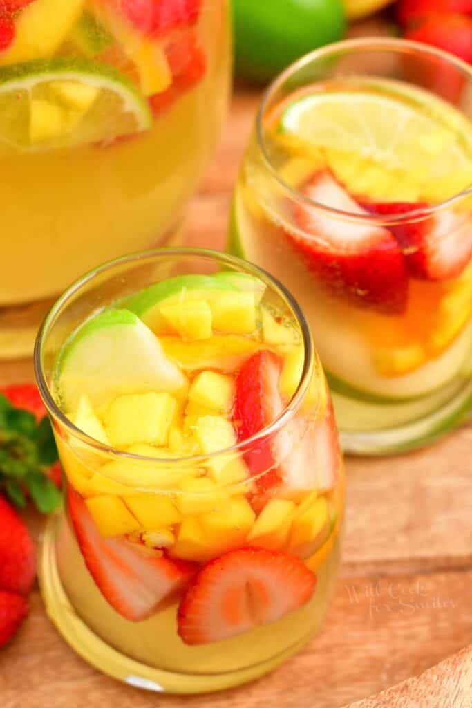 Two glasses are filled with fruit and white sangria. 