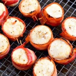 Cooked bacon wrapped scallops are on a wire rack.