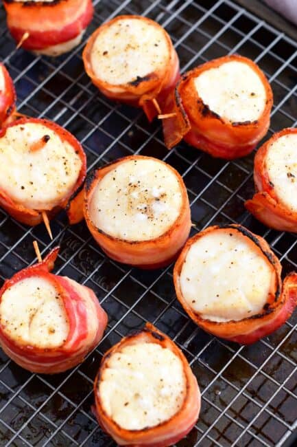 Crispy pieces of bacon are wrapped around cooked scallops.