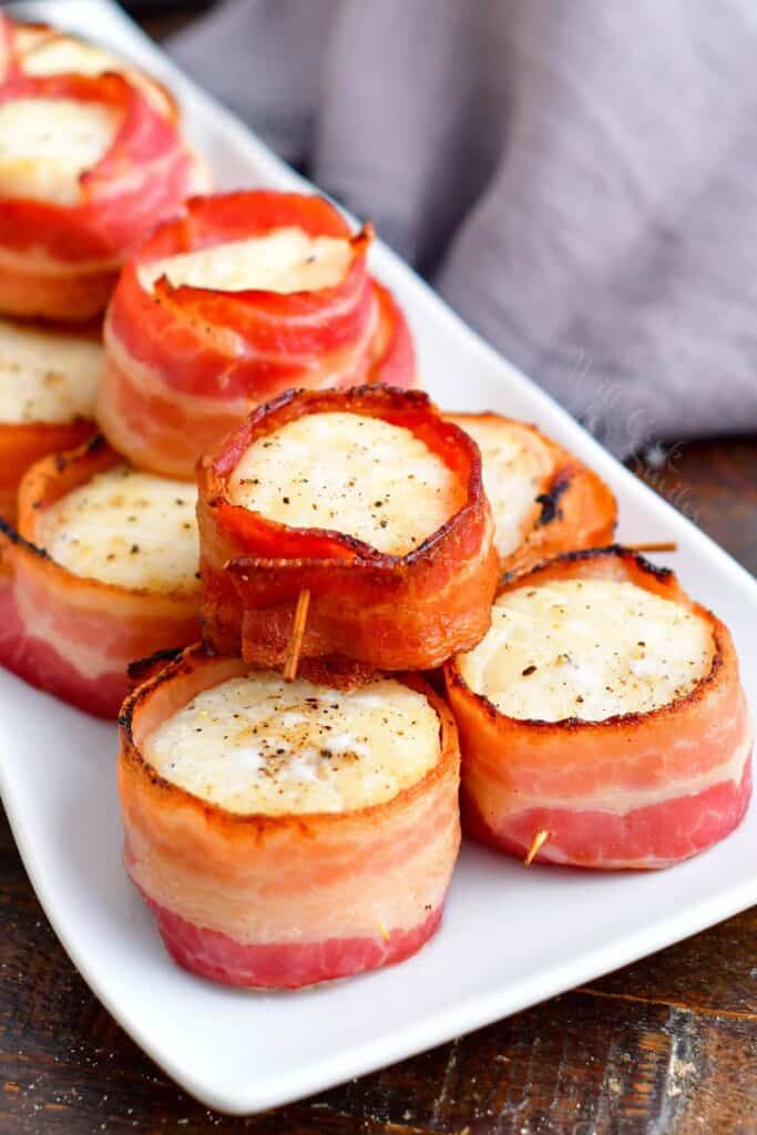 A serving of scallops is on a white plate and ready to be eaten. 