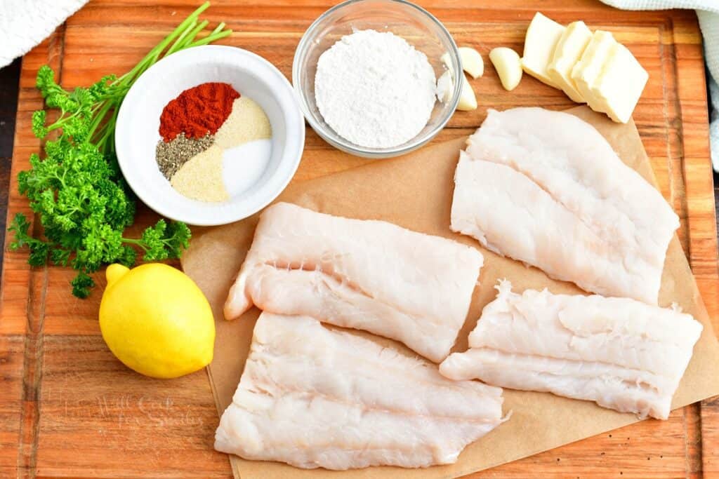 The ingredients for baked cod are placed on a wooden cutting board.