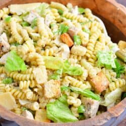 The tossed pasta salad is presented in a large wooden bowl.