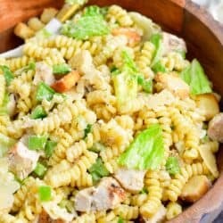 Chicken caesar pasta salad is in a large wooden bowl.