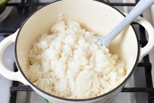 Coconut rice is being stirred by a large spoon. 