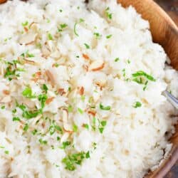 Coconut rice is fluffed and presented in a large serving bowl.