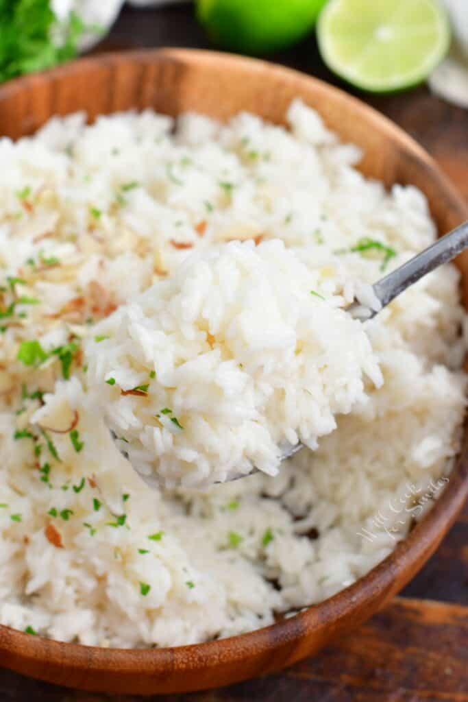 A spoon is lifting a small portion of rice from the bowl. 