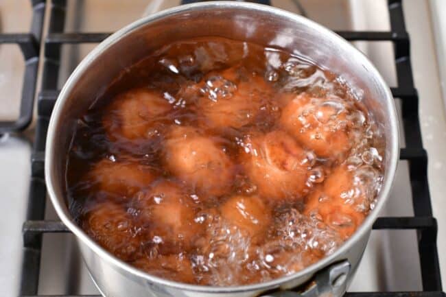 Whole potatoes are in a pot of boiling water. 