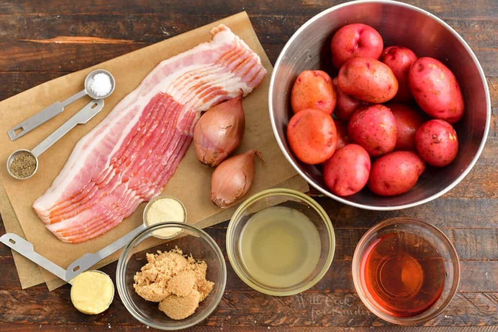 The ingredients for German potato salad are placed on a dark surface. 