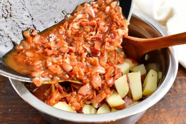 The bacon dressing and potatoes are being combined. 