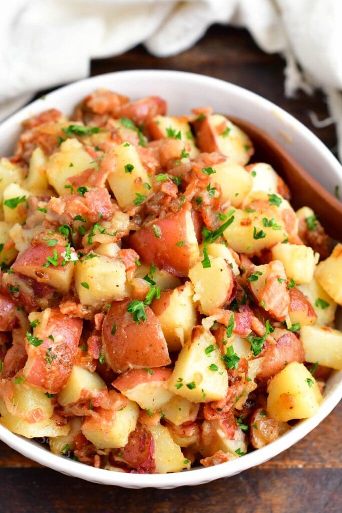 A white bowl is filled with German potato salad. 