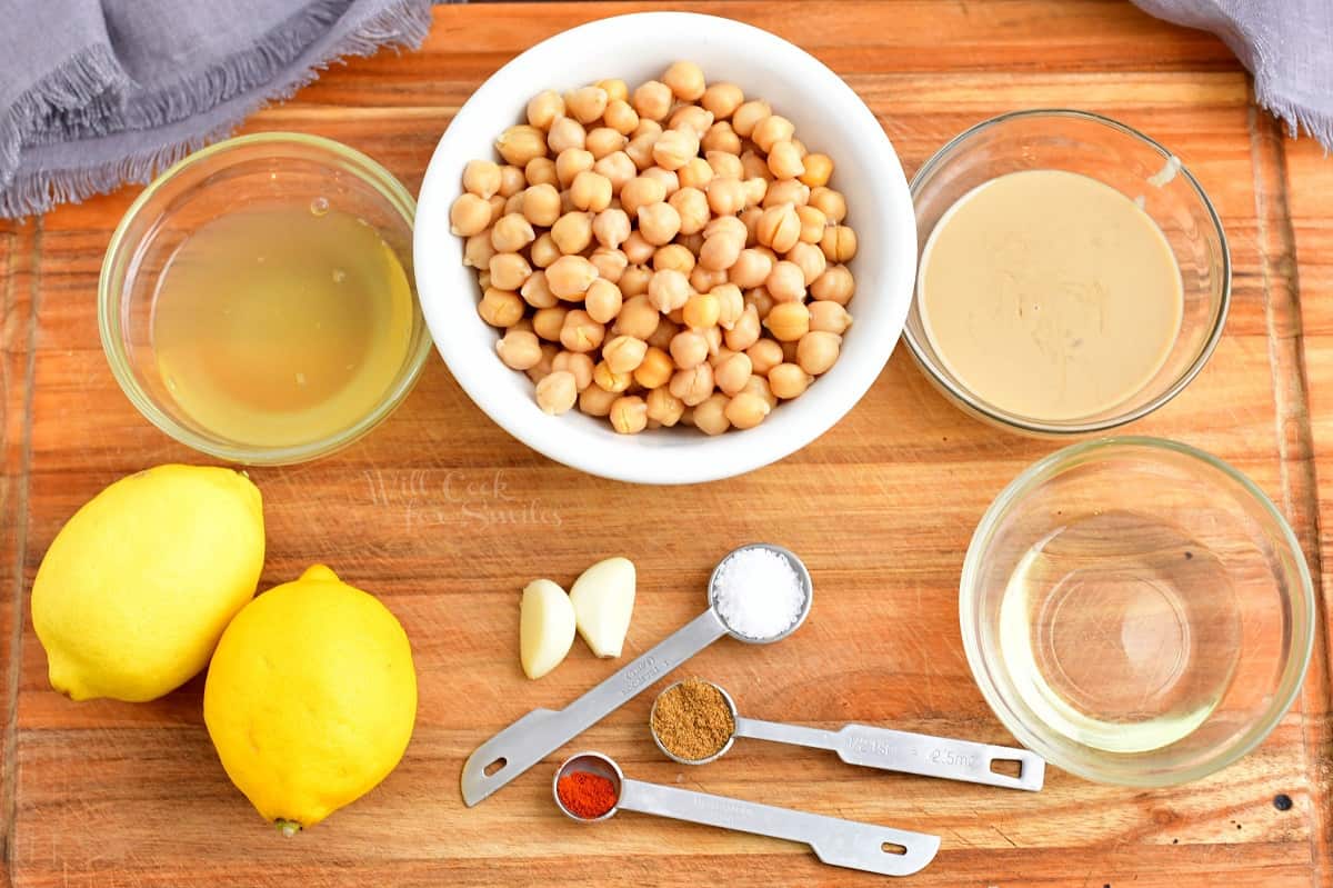 The ingredients for hummus are placed on a wooden cutting board.