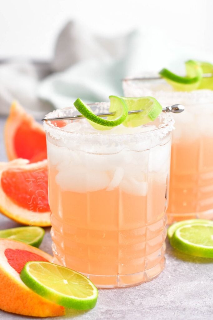 A pink paloma is garnished with lime.