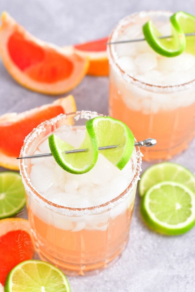 Wedges of lime and grapefruit surround two palomas. 