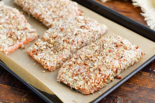Pecan crusted salmon is uncooked on a baking sheet.