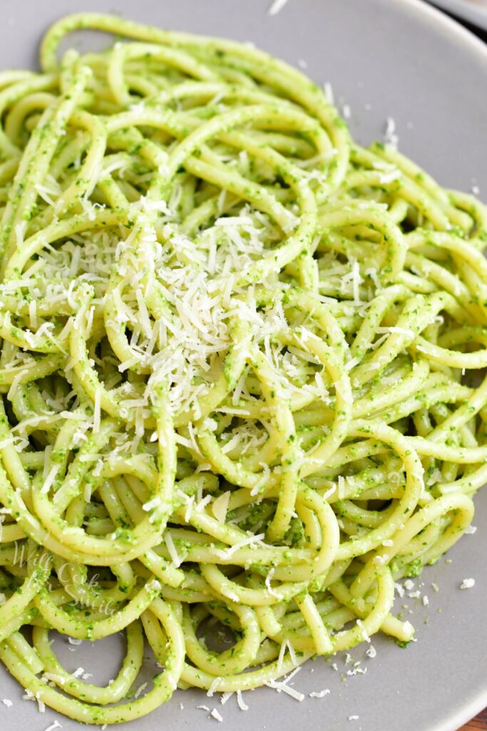 Pesto pasta is plated and sprinkled with parmesan. 