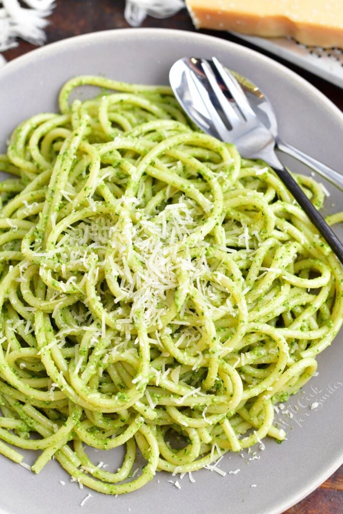 A fork is placed on the side of a serving of pesto pasta.