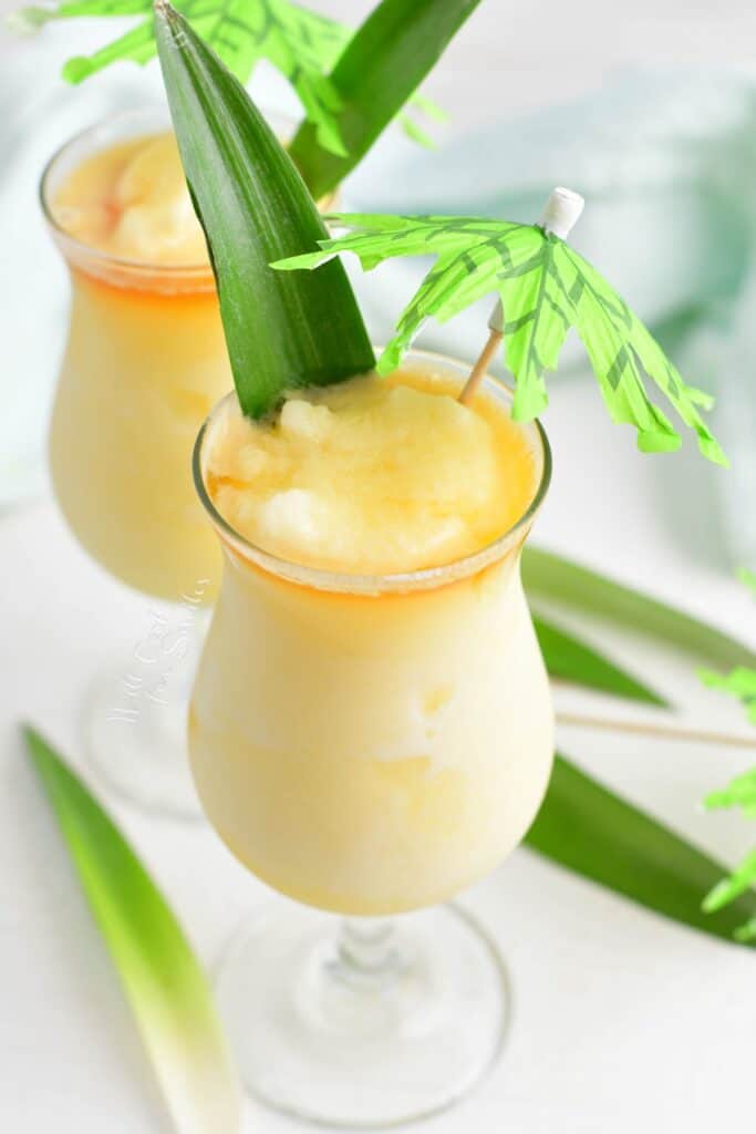 A pineapple leaf and mini umbrella garnish a pina colada.