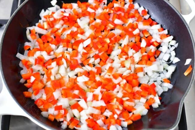 Onions and peppers are chopped and placed in a skillet.