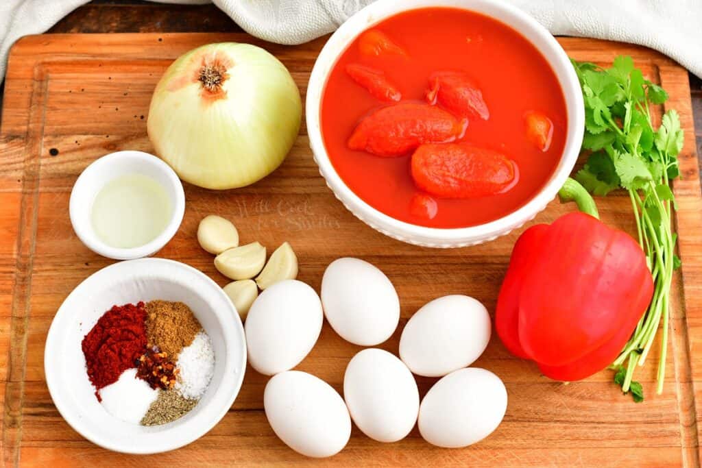 The ingredients for shakshuka are placed on a wooden cutting board. 