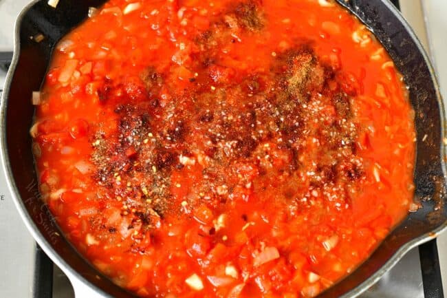Seasonings have been added to the tomato mixture in the skillet.