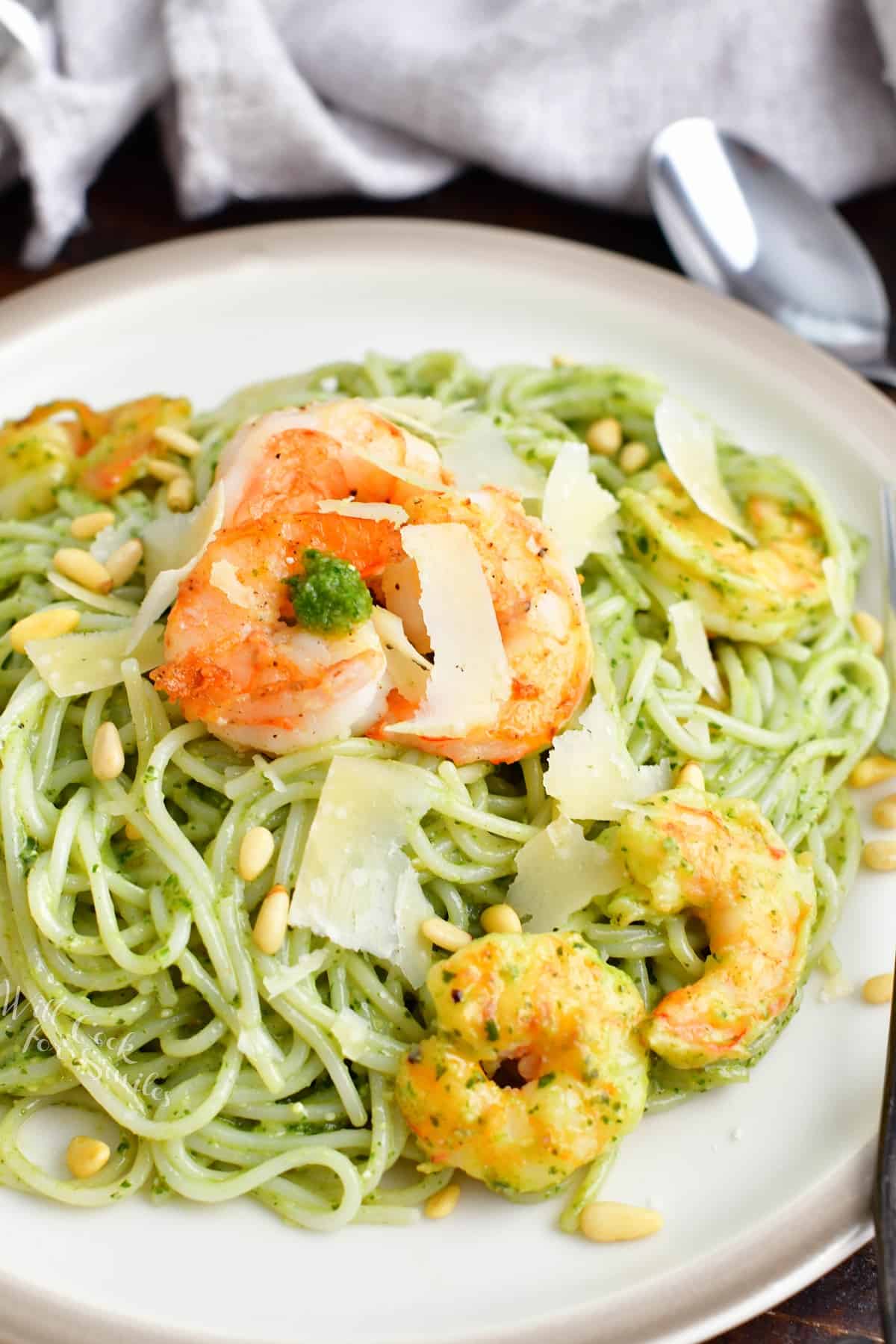 Shrimp and cheese garnish a large potion of pesto pasta. 