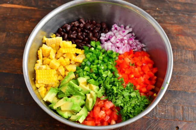 All of the ingredients for corn salad are in a large mixing bowl. 