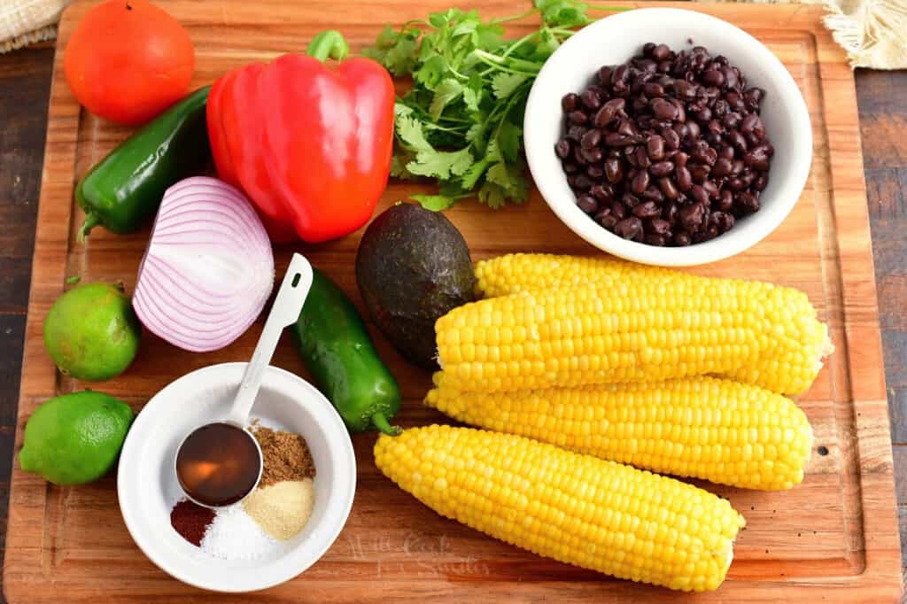 The ingredients for black bean and corn salad are on a wooden surface. 