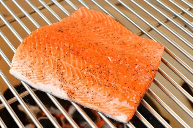 Raw salmon is on a grill.