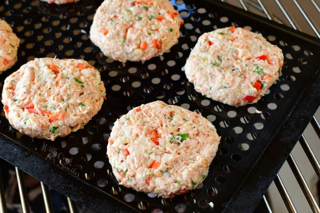 Uncooked patties are on a grill basket.