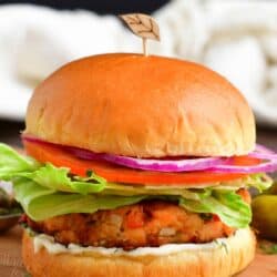 A salmon burger is placed on a wooden surface.