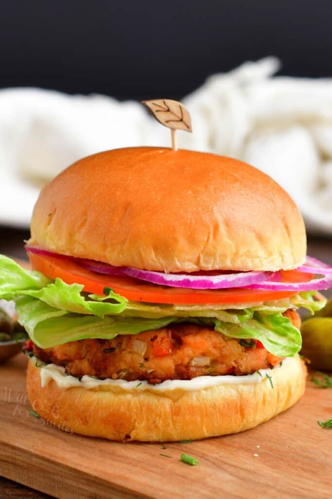 A salmon burger is placed on a wooden surface.