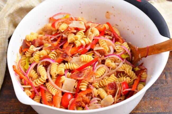 Pasta salad is tossed in a large bowl. 