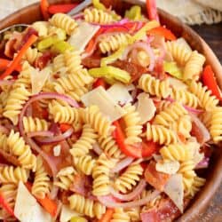 All of the ingredients for pasta salad have been thoroughly tossed in a large bowl.