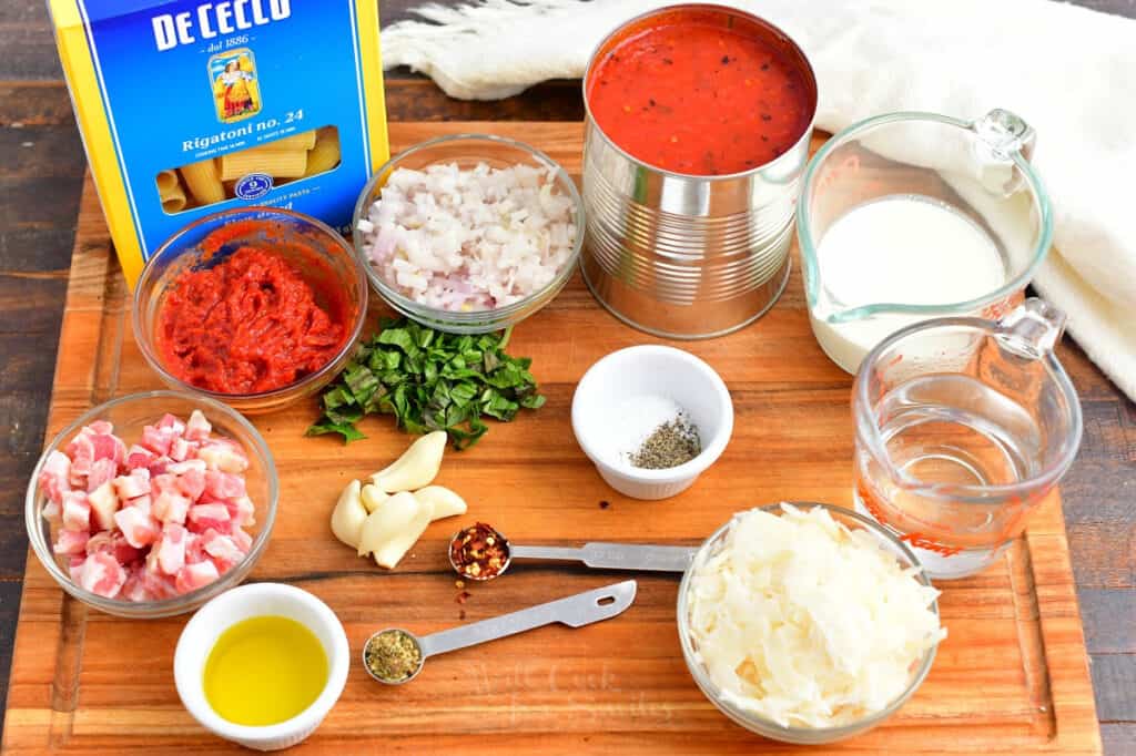 Penne alla vodka ingredients are placed on a wooden board. 