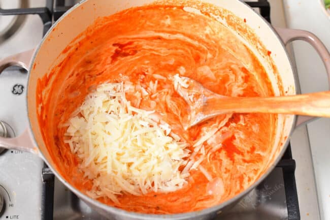 Parmesan and cream are being stirred into a pot. 