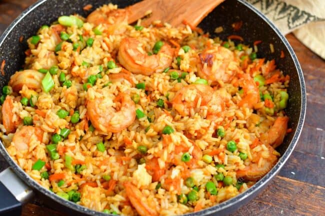 Shrimp fried rice is fully cooked in a black pan.