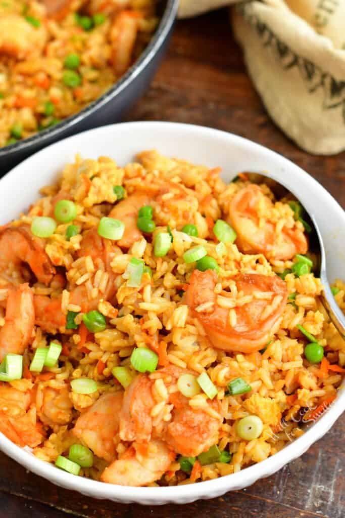 A small white bowl is filled with shrimp fried rice.