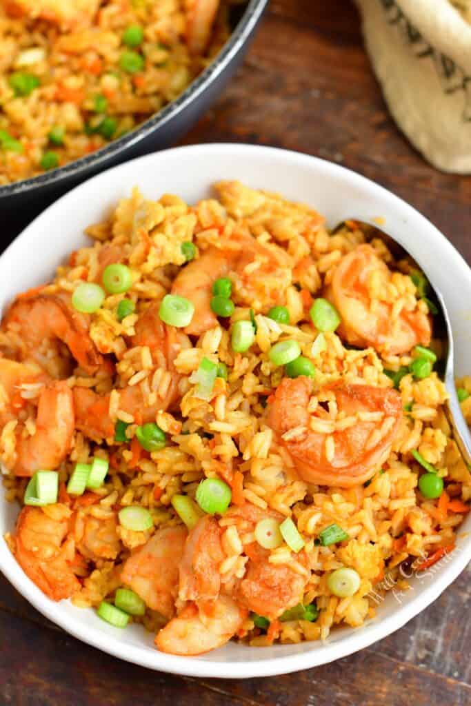 Shrimp fried rice is in a white bowl with a spoon.