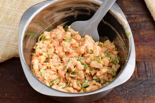 A silver bowl is filled with shrimp salad. 