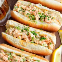 Four stuffed shrimp rolls are lined up on a dark surface.