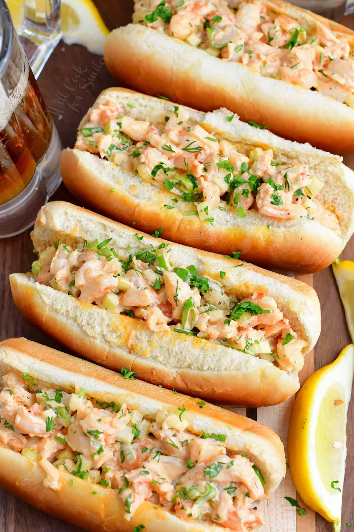 Four stuffed shrimp rolls are lined up on a dark surface. 