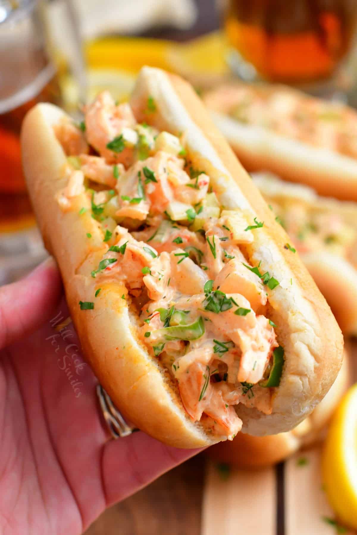 A shrimp roll is held in a hand. 