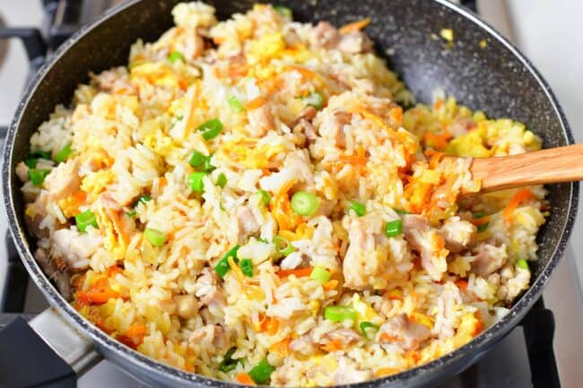 stirring fried rice in a large pan