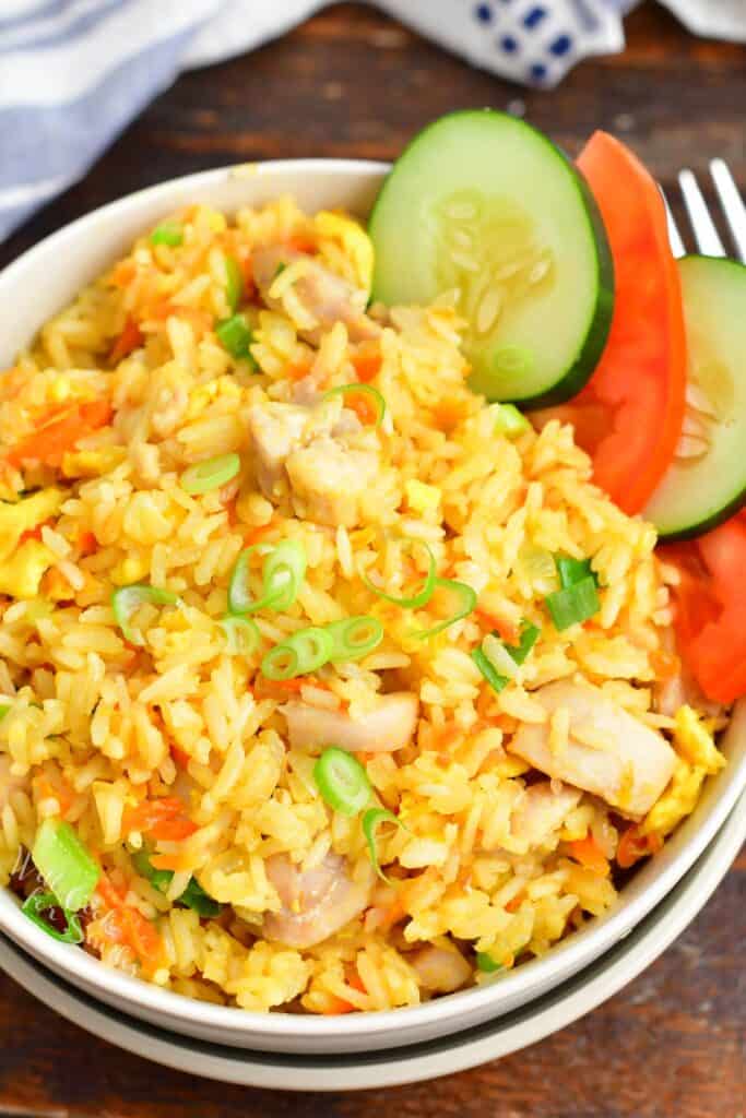 Top view of Thai fried rice in a bowl with cucumber and tomato slices