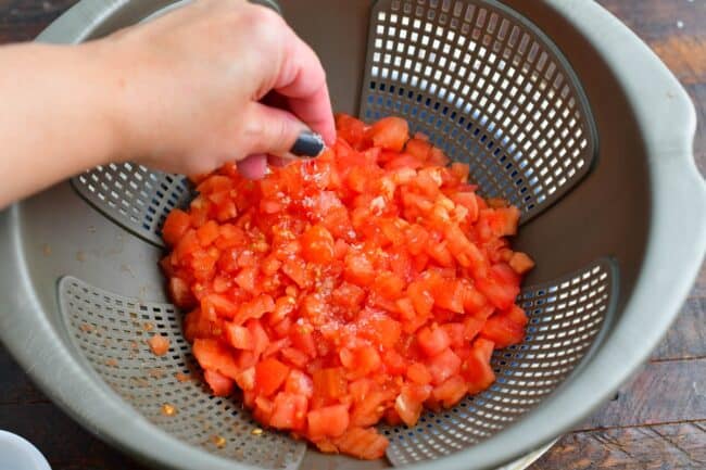 salting diced tomatoes in a colander