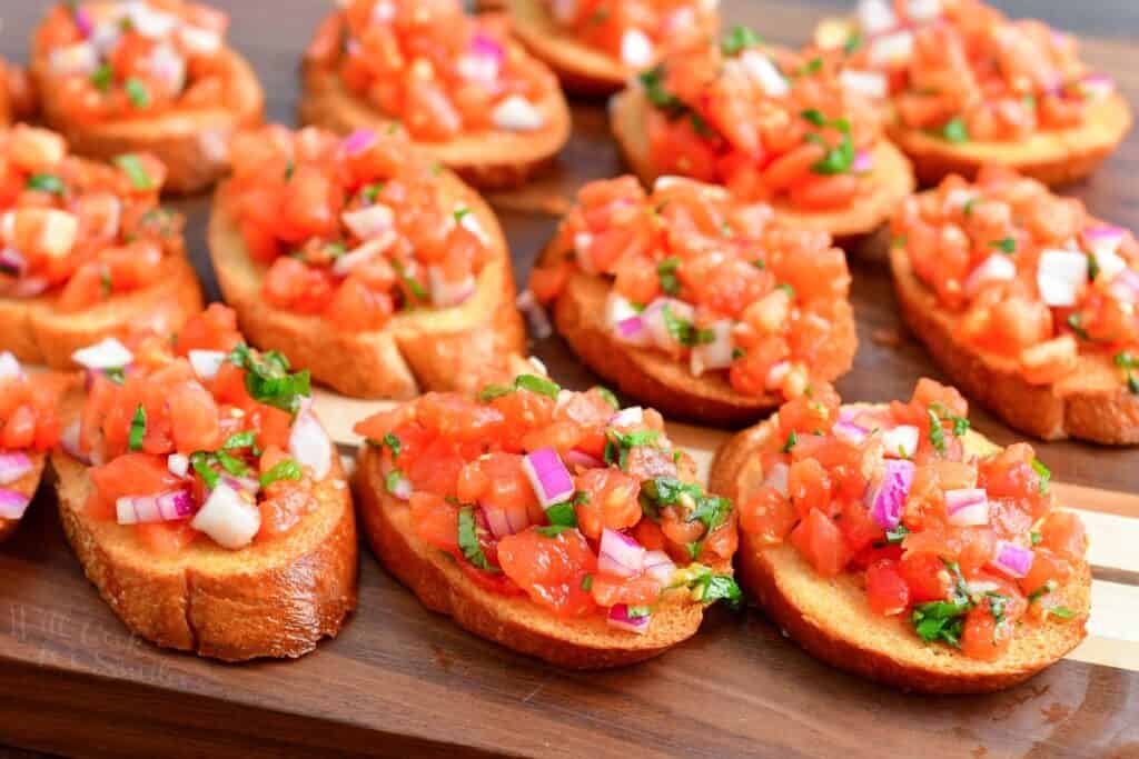 sliced of toasted bread laid out on the cutting board topped with tomato mixture