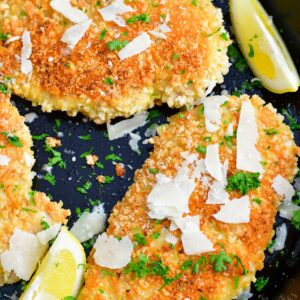 Three cooked chicken breasts are garnished in a large black cooking pan.